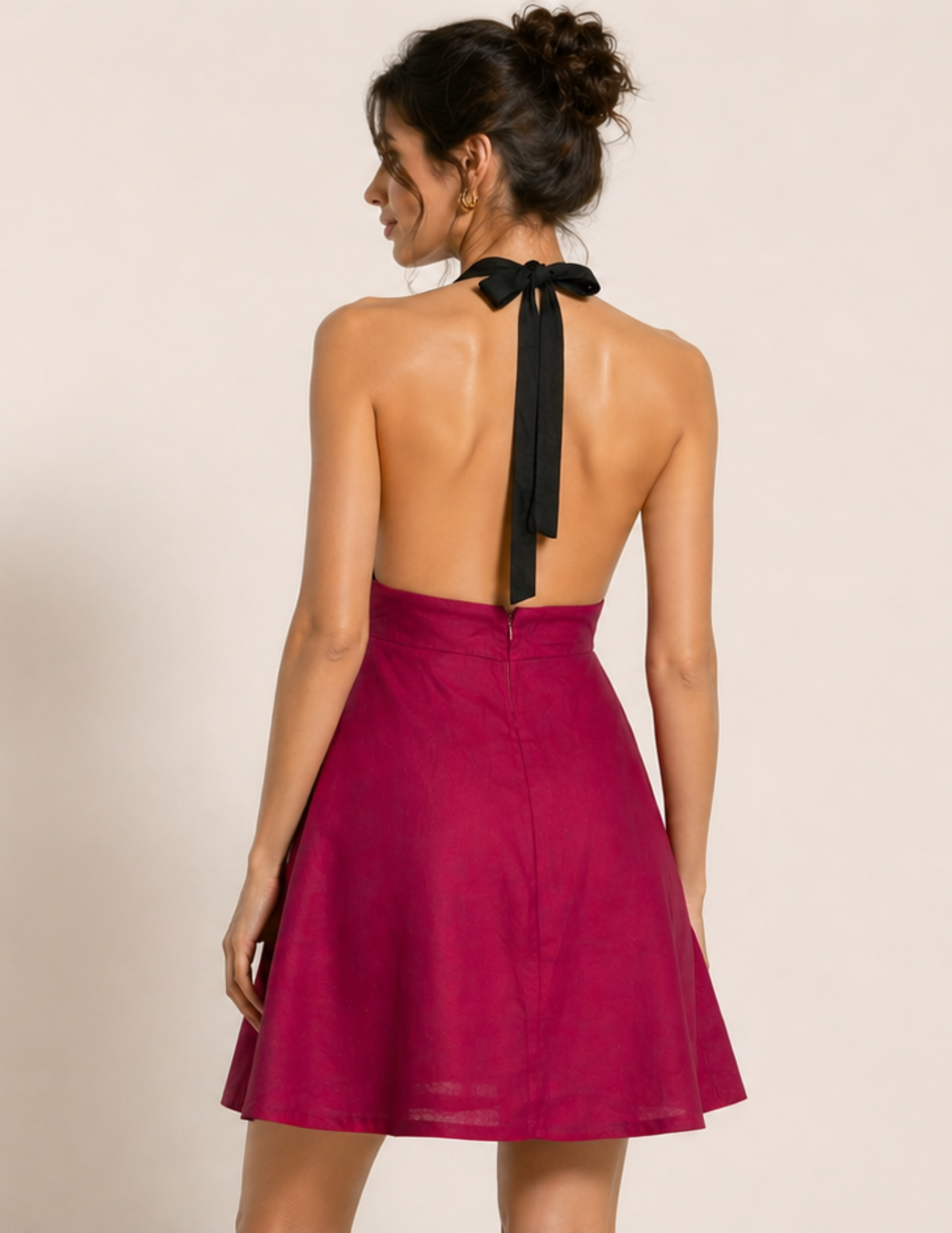 Woman wearing a red dress with a black halter neck on a beige background