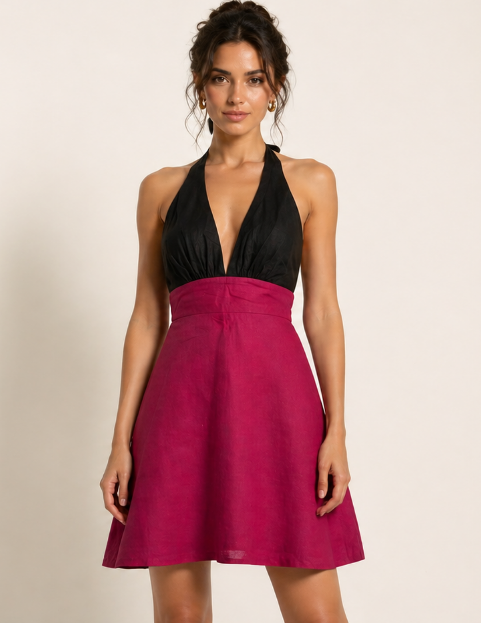 Woman wearing a black halter top and pink skirt dress on a beige background