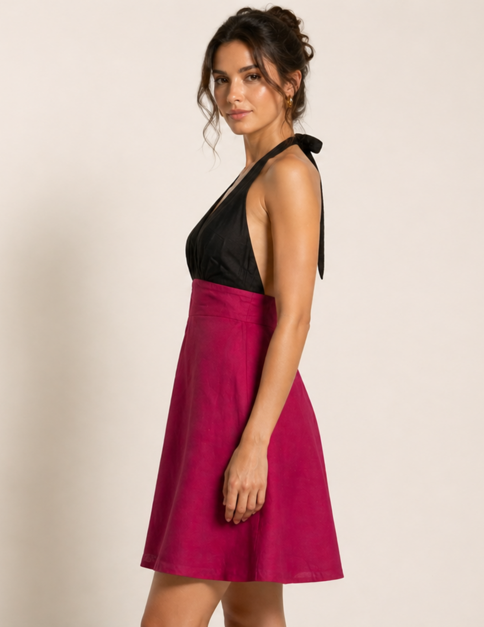 Woman wearing a black and pink dress with a bow detail on a beige background