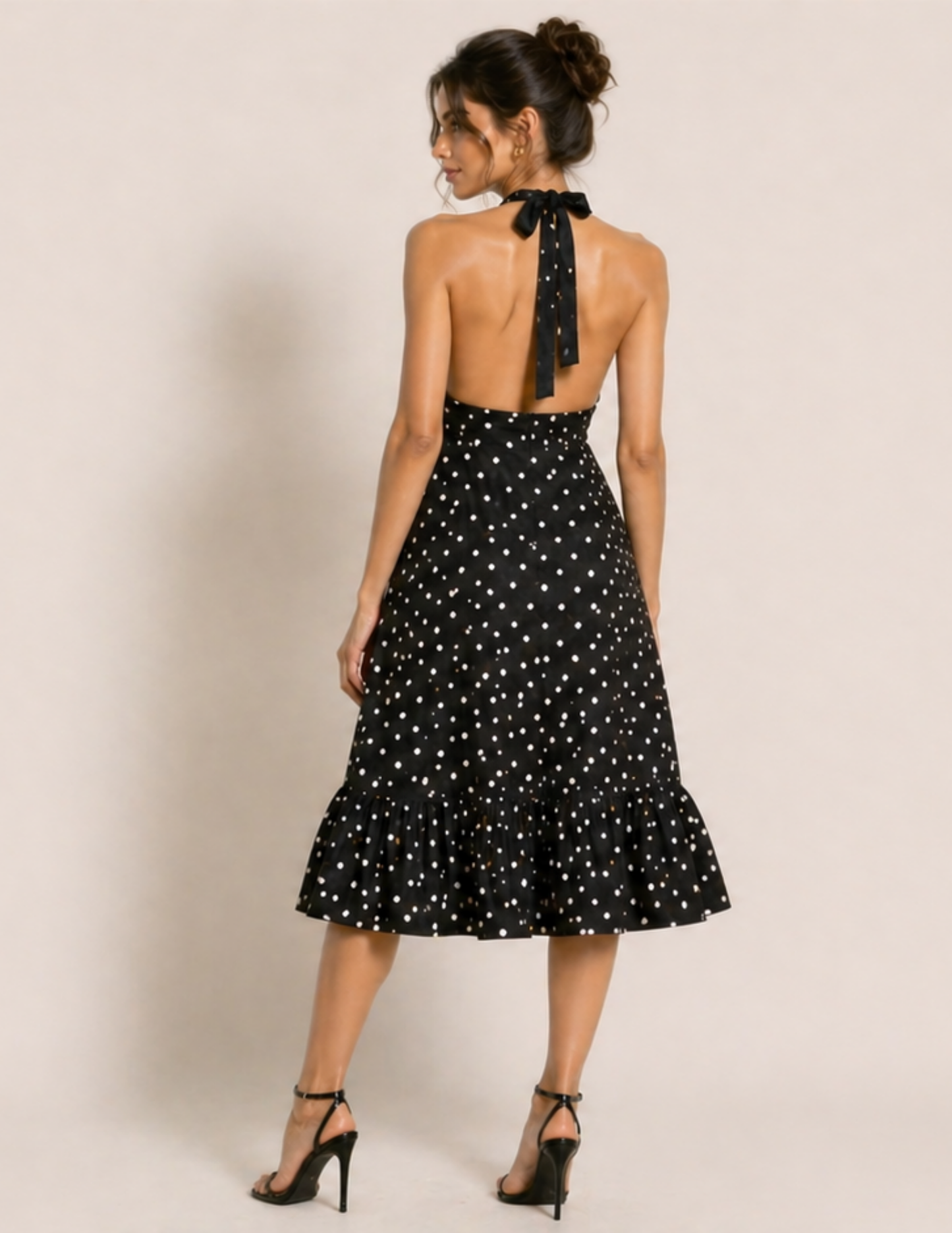 Woman wearing a black dress with white polka dots on a plain background