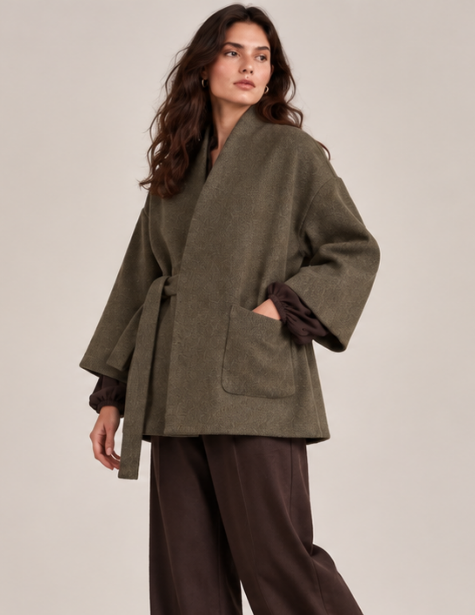 Women's oversized kimono wrap coat sewing pattern shown in olive green textured fabric, featuring a shawl collar, wide sleeves, waist tie, and rounded patch pocket.