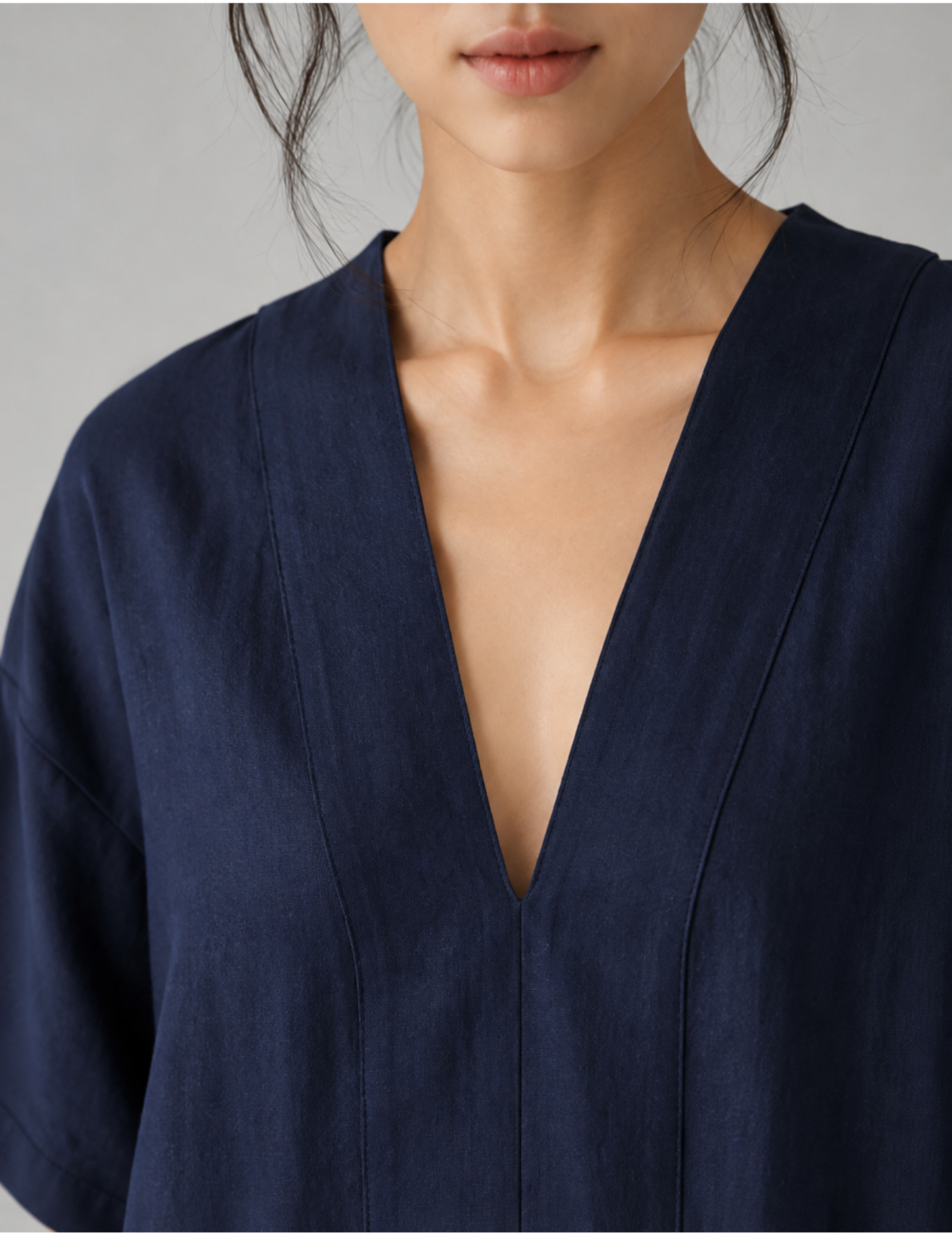 Close-up of a model wearing a navy blue V-neck top with a deep plunging neckline and wide short sleeves, set against a neutral gray background.  women's dress sewing pattern